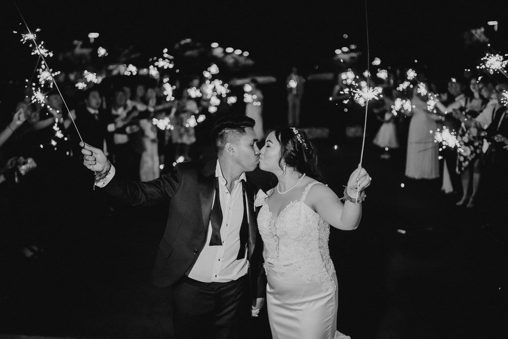 Couple dances with sparklers at nighttime wedding celebration.