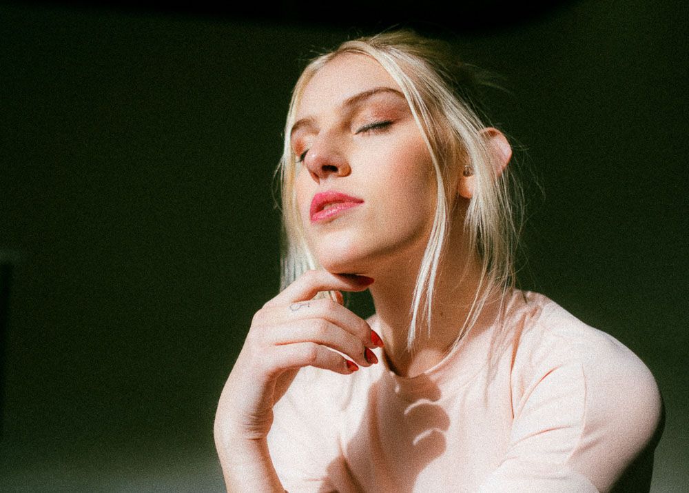 Artistic portrait in soft lighting against green background.