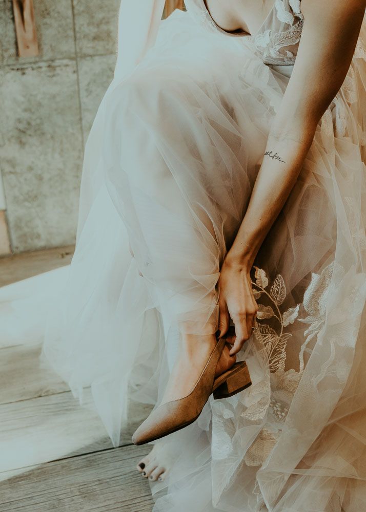 Close-up details of delicate white tulle and lace from a wedding dress against wooden flooring.