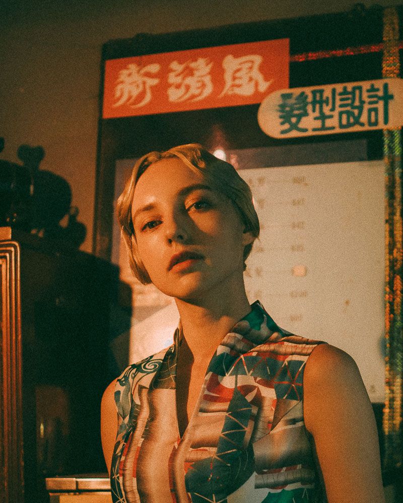 Vintage-inspired portrait with Asian signage and warm lighting.