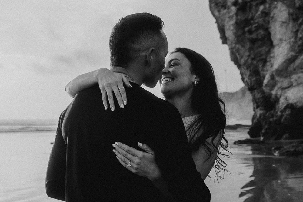 An intimate coastal photoshoot capturing candid moments between a couple near ocean cliffs.