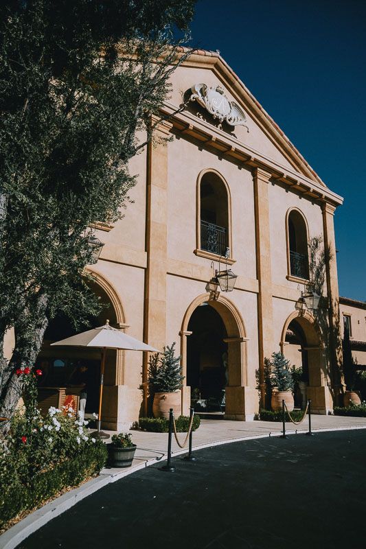 Classical church facade with arched windows and cream colored exterior under blue sky.