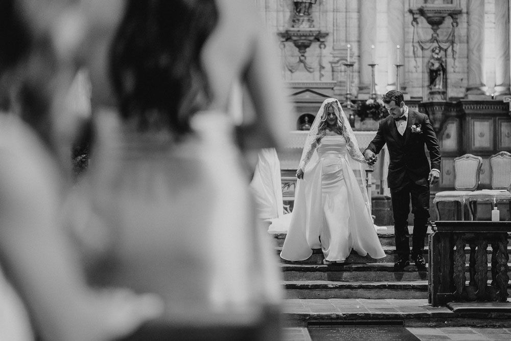 Black and white church ceremony photo captured from behind wedding guests.