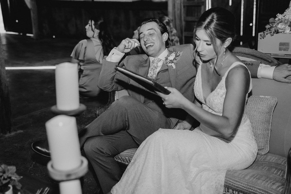 Wedding couple sharing laughs while looking at a book during their reception.
