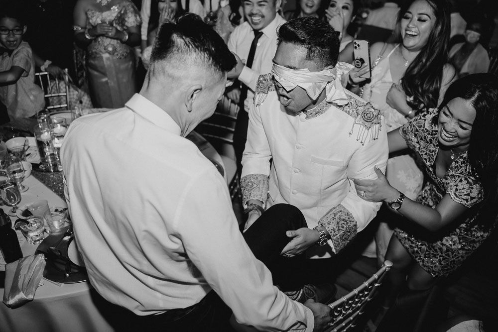 Black and white photo capturing lively dancing and celebration at a wedding reception.