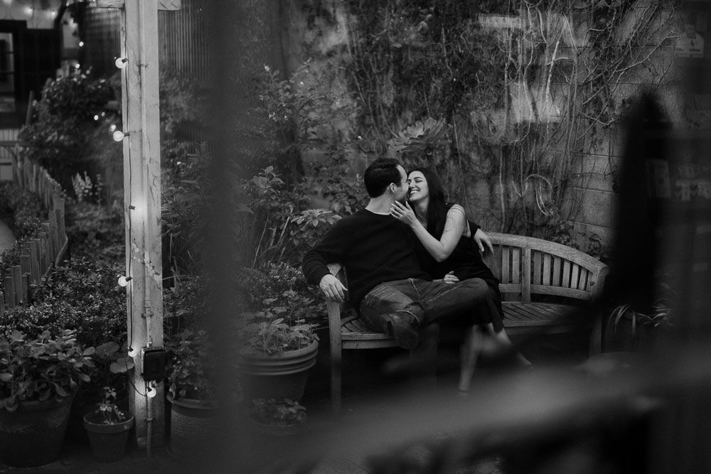 Silhouetted figures embrace in a lush garden setting with dramatic lighting.