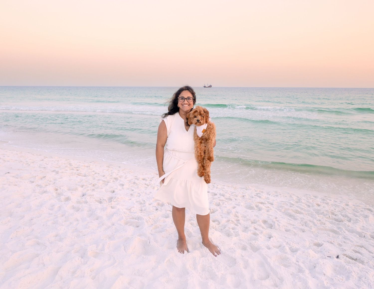 People walking along pristine white sand beach during golden hour sunset.