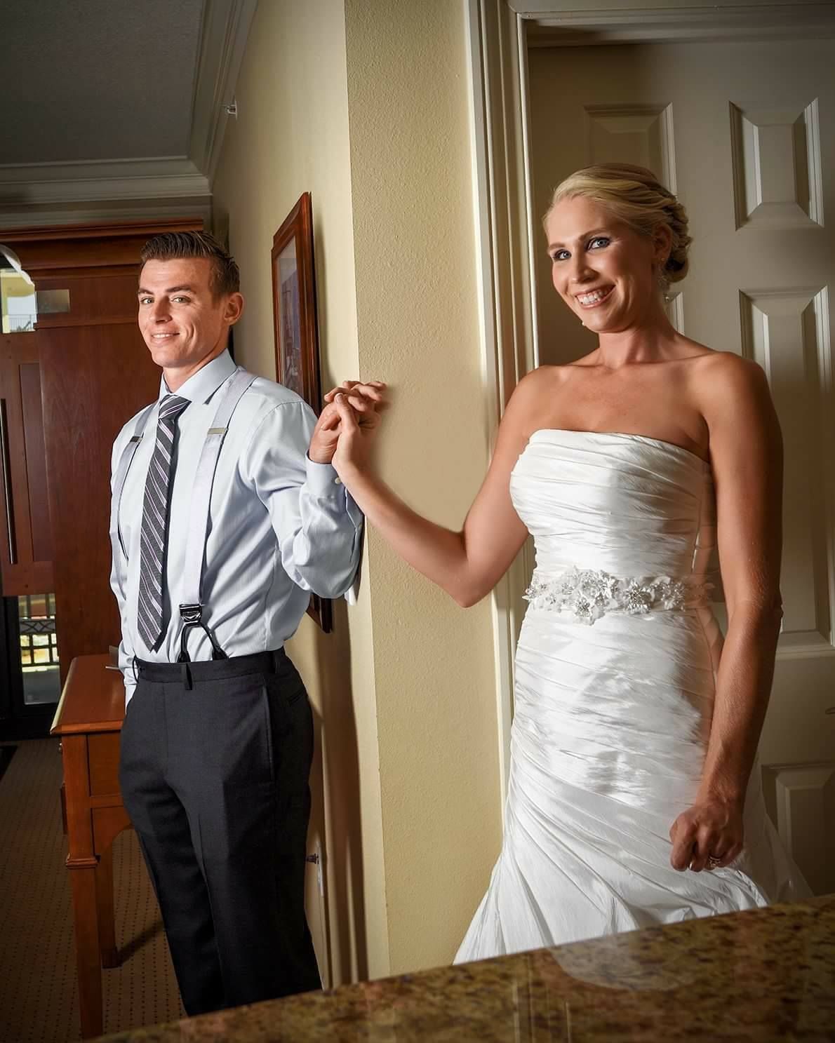 A couple shares a playful moment on their wedding day in formal attire.