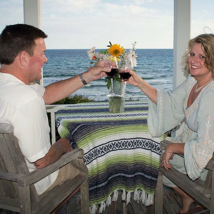 A series of photos showing a couple enjoying a romantic dinner by the ocean at sunset.