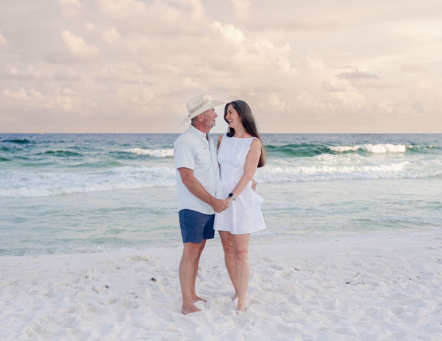 Couples enjoying a romantic moment on a pristine beach with rolling waves and soft evening light.