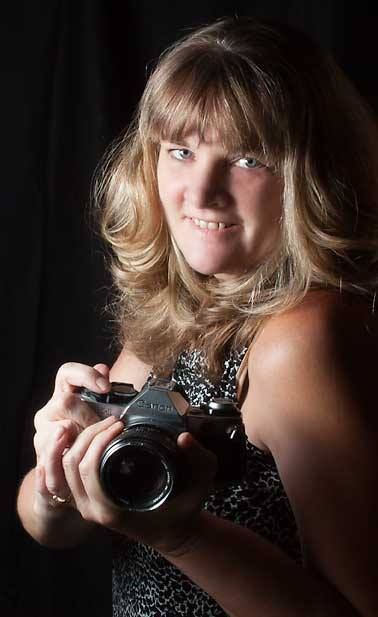 Artistic portrait series of photographer with camera in dark setting with dramatic lighting.