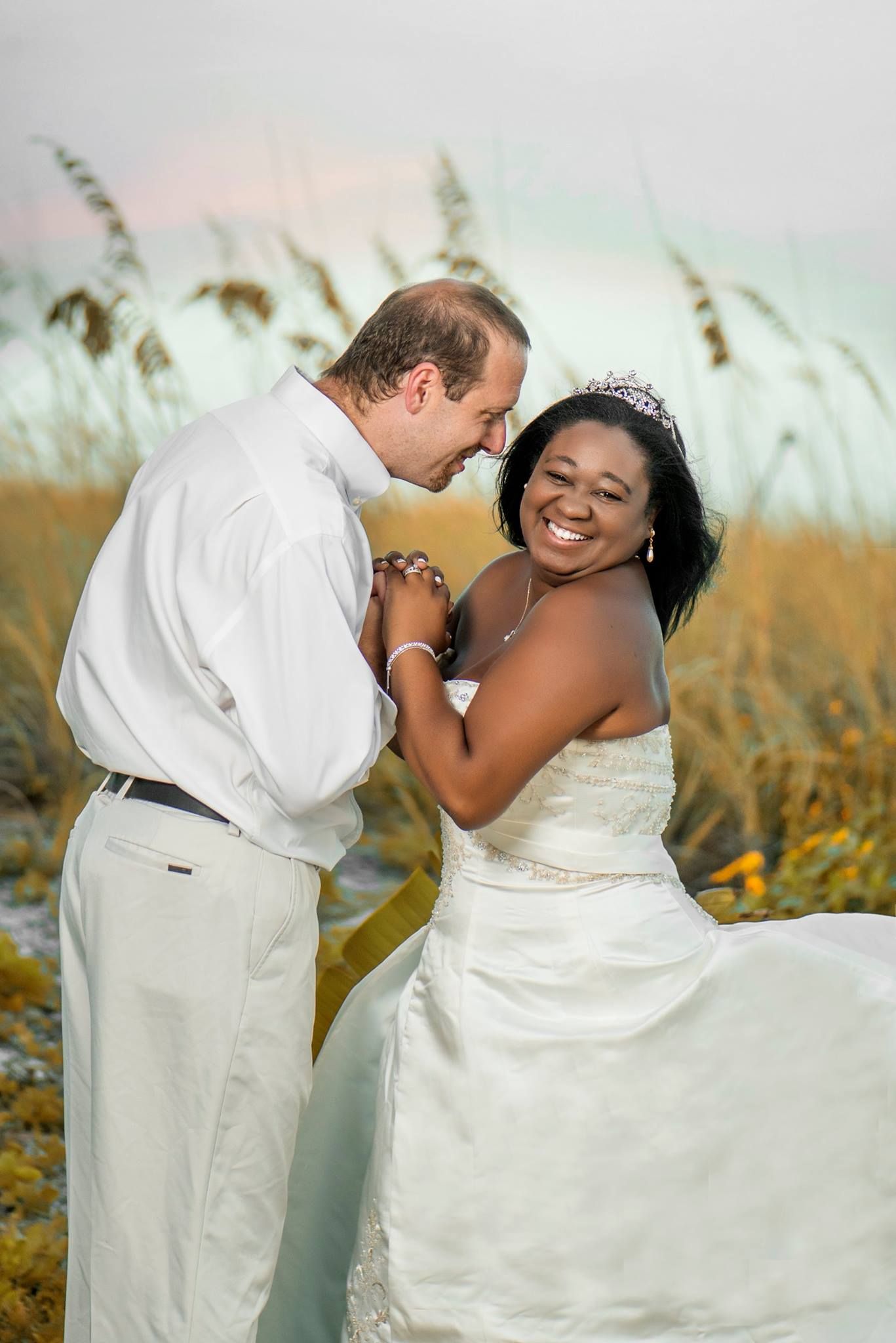 Newlyweds sharing intimate moments in a field of golden sea oats during a beach wedding photoshoot.
