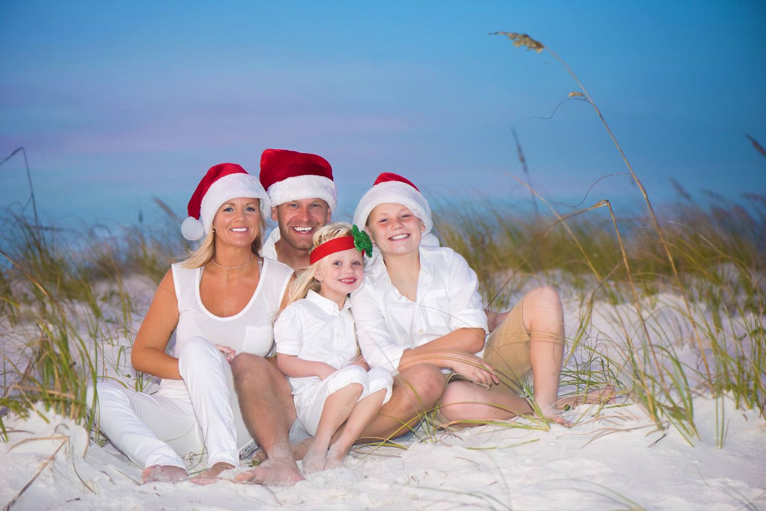 Family portrait session on pristine white sand beach with sea oats and blue skies.