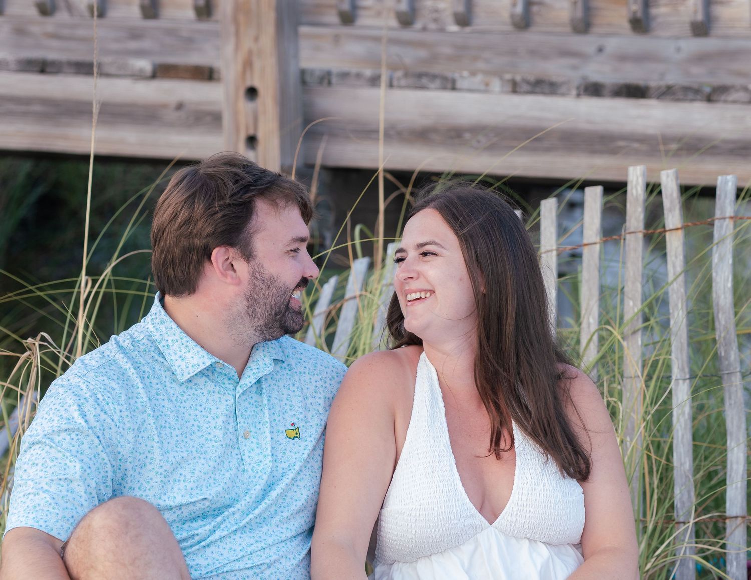 Couple sharing joyful moment on wooden boardwalk near beach at sunset.