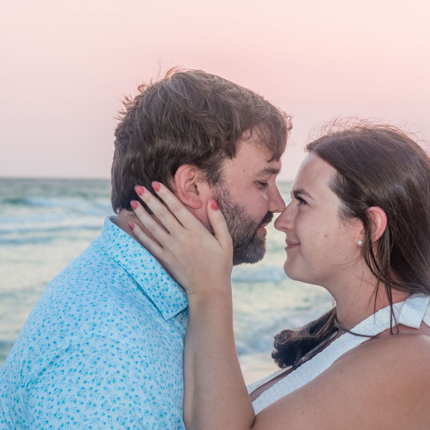 Intimate romantic moment captured between couple on beach at sunset.