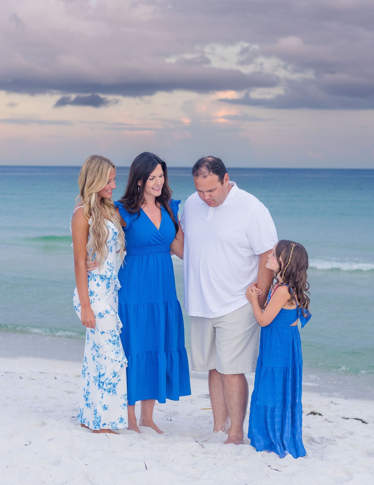 Family portrait session on white sandy beach with turquoise ocean backdrop.