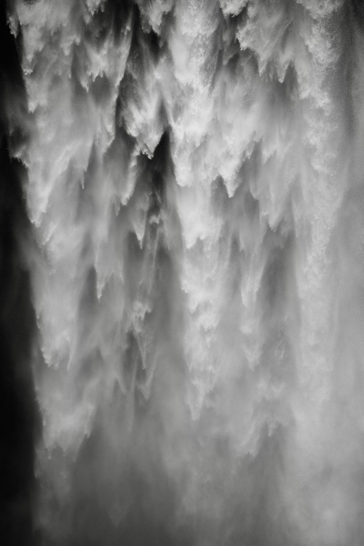 Black and white abstract image of flowing water creating misty, ethereal patterns with dramatic contrast and texture.