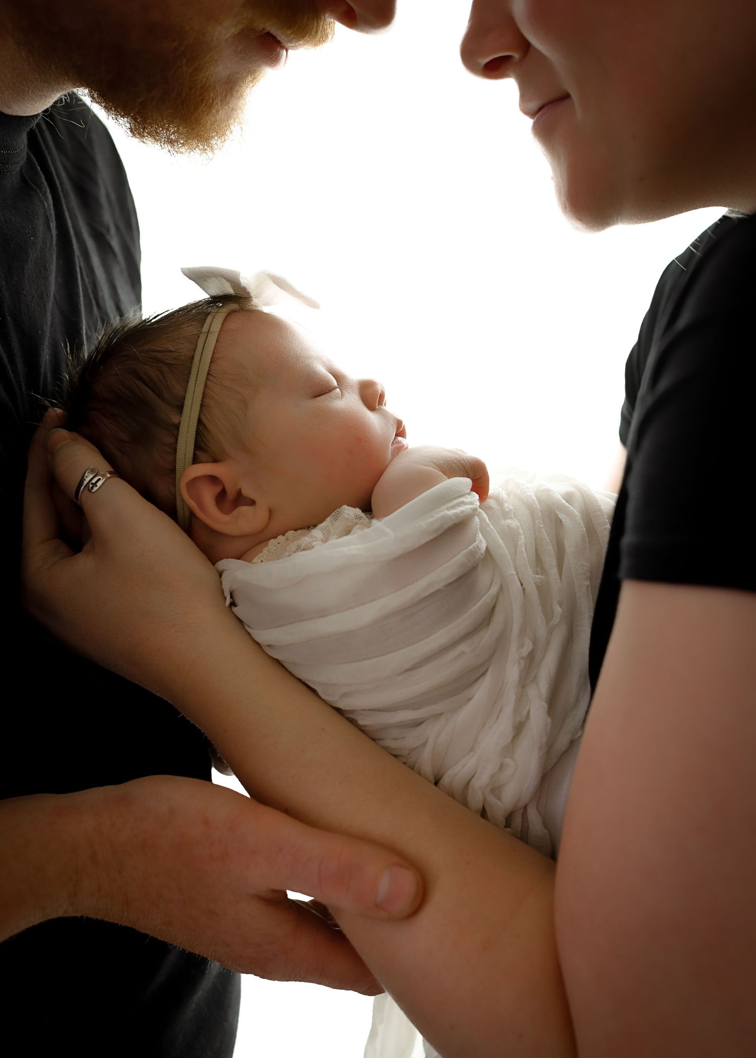 Tender moments between parent and baby captured in backlit series.
