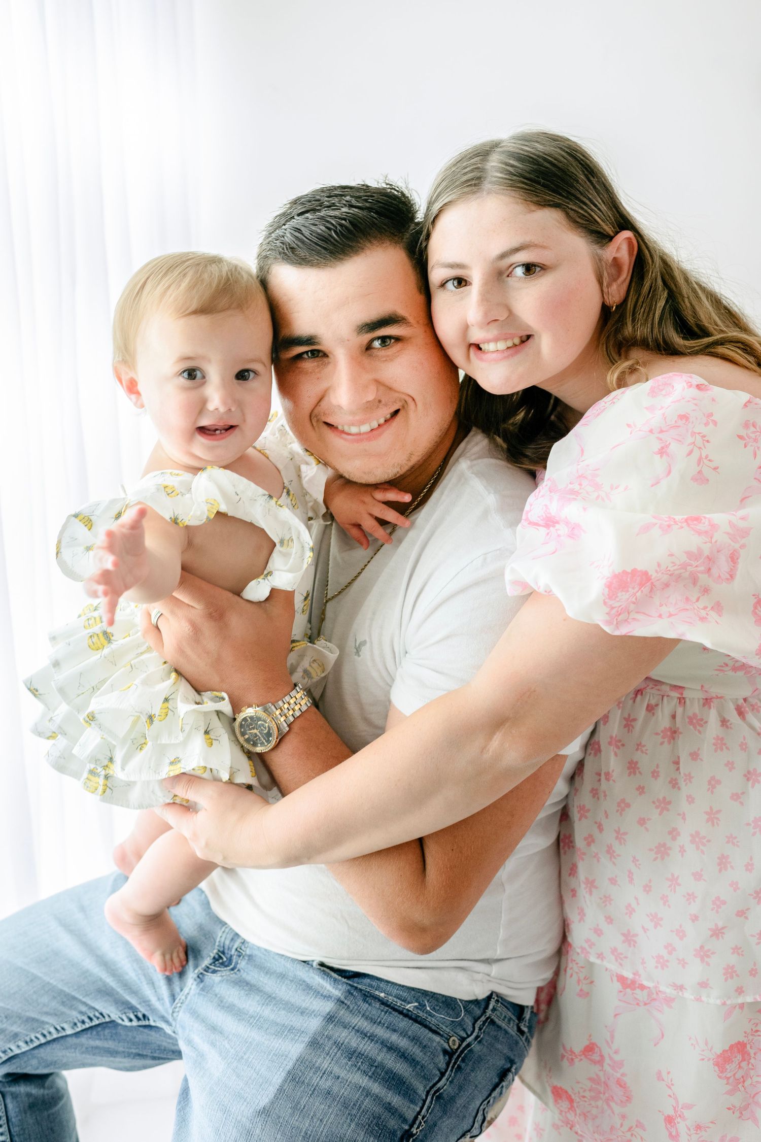 Intimate indoor family portrait session with soft lighting and white backdrop.