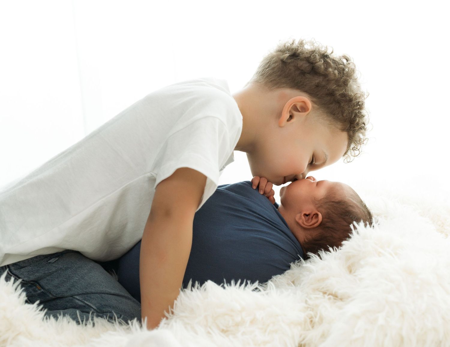 A tender moment between parent and child lying together on a soft white furry rug.
