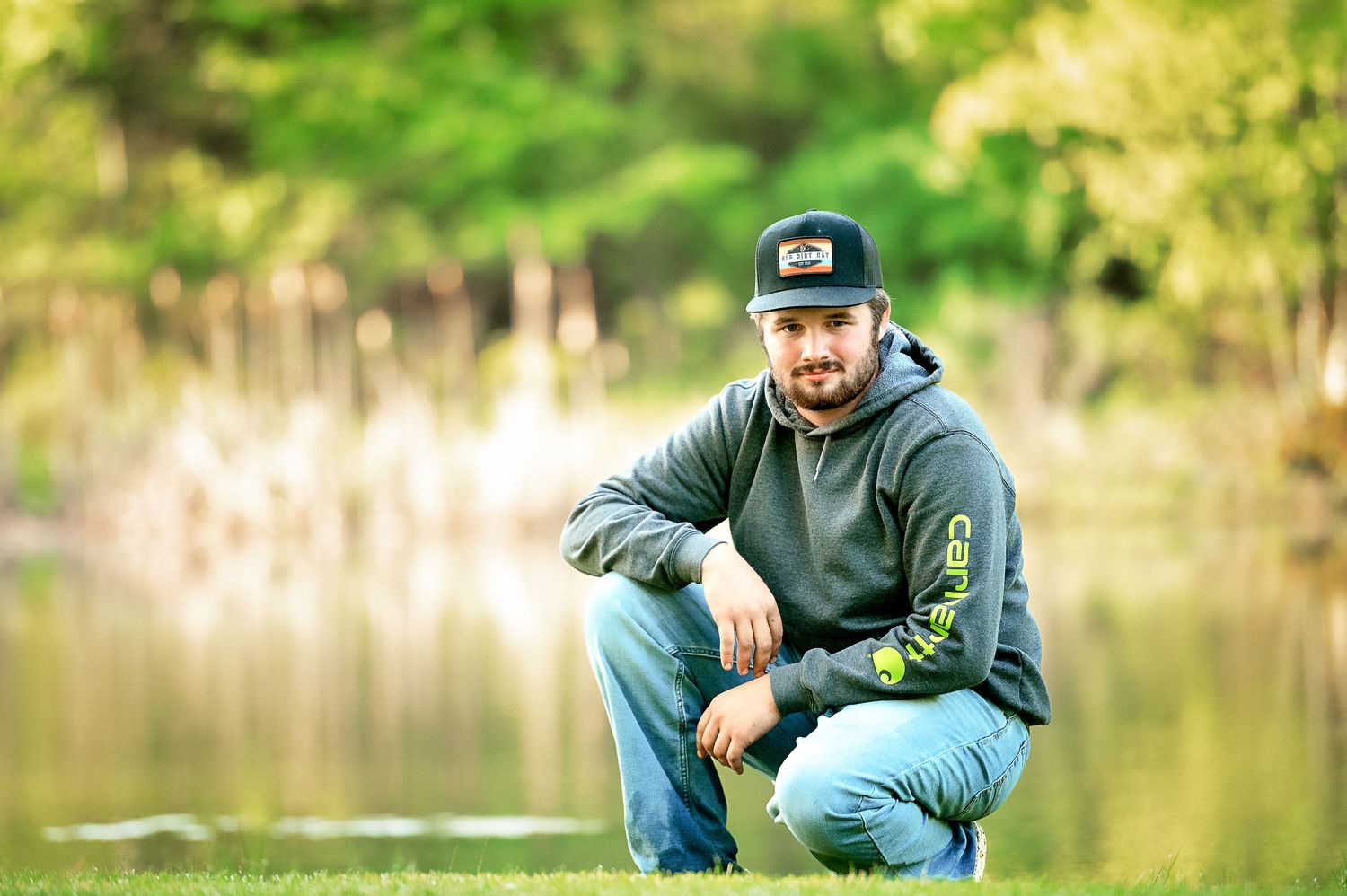 Casual outdoor portraits near a lake with natural green background.