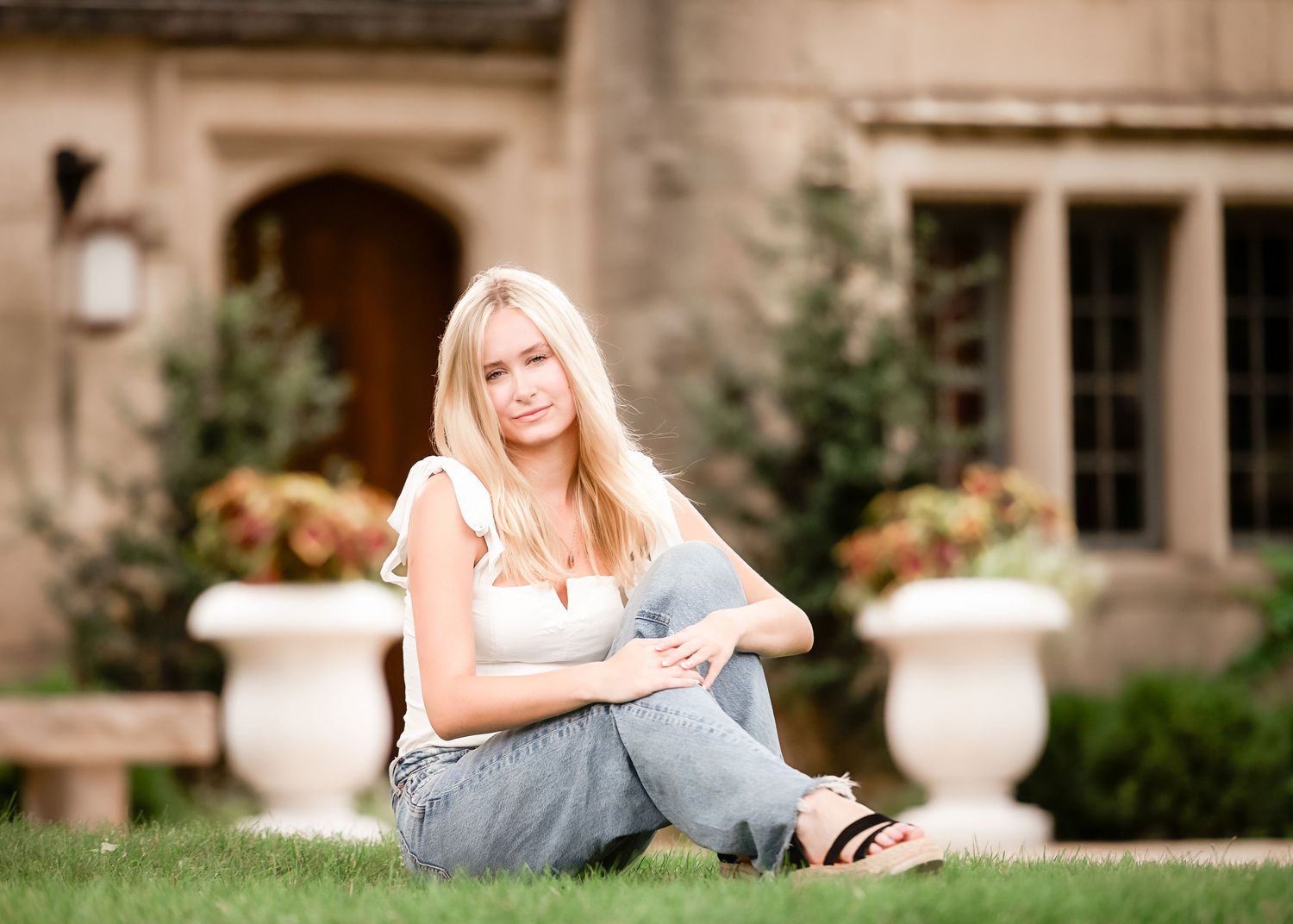 A casual outdoor portrait on a manicured lawn with ornate stone architecture in the background.