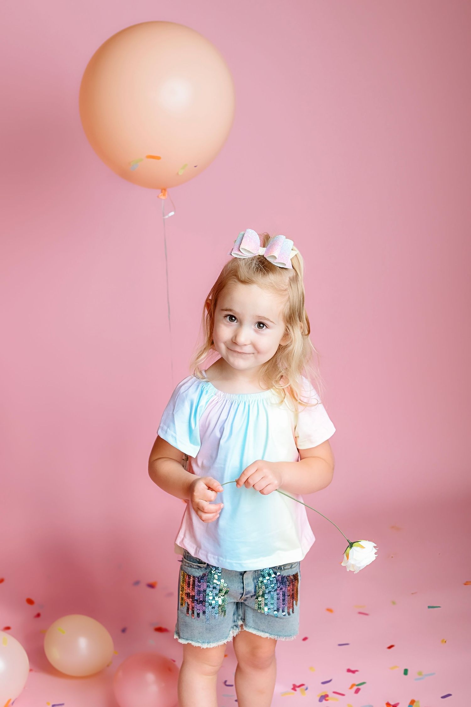 Pink balloon party setup with confetti scattered on floor.