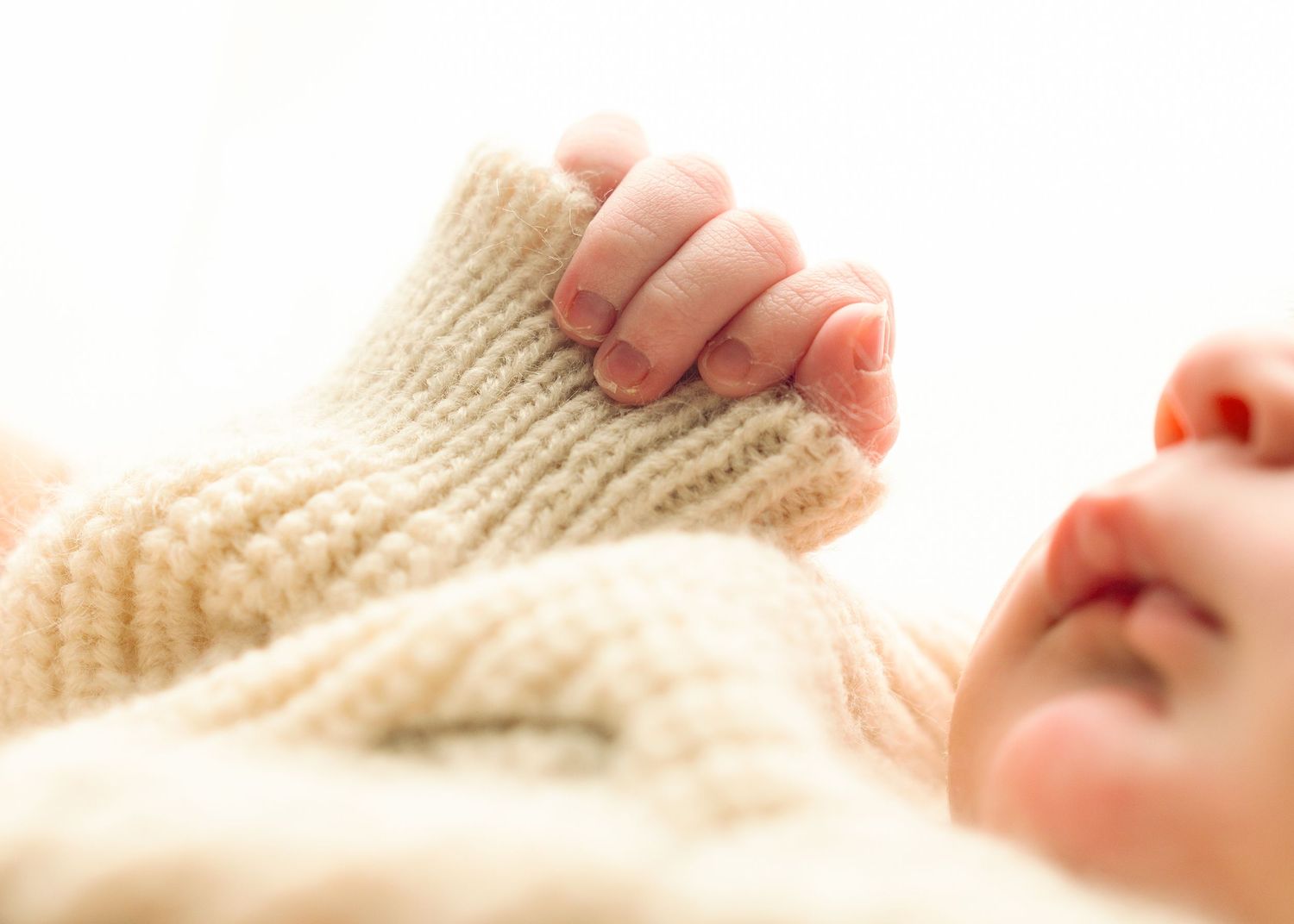 Close-up of tiny newborn baby feet wrapped in cozy knit blanket.