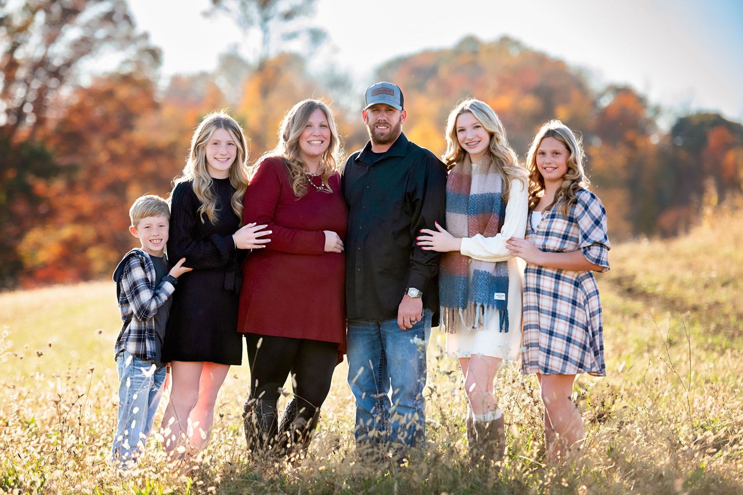 Group portrait of family members gathered outdoors during autumn season.