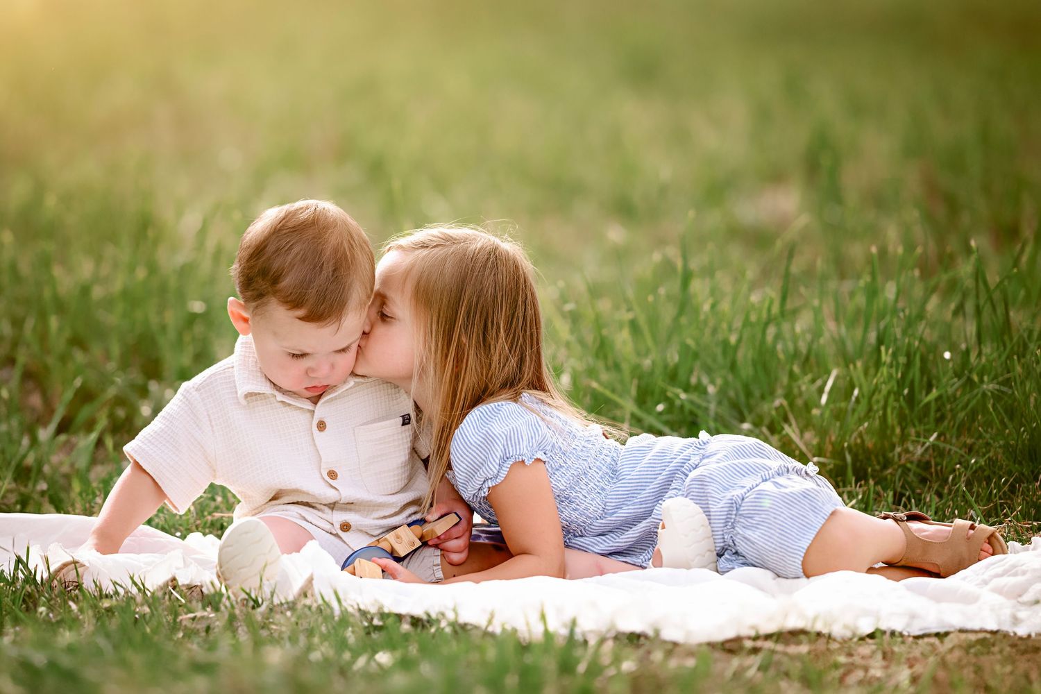 Sweet intimate moments shared between family members laying on a blanket in a meadow.