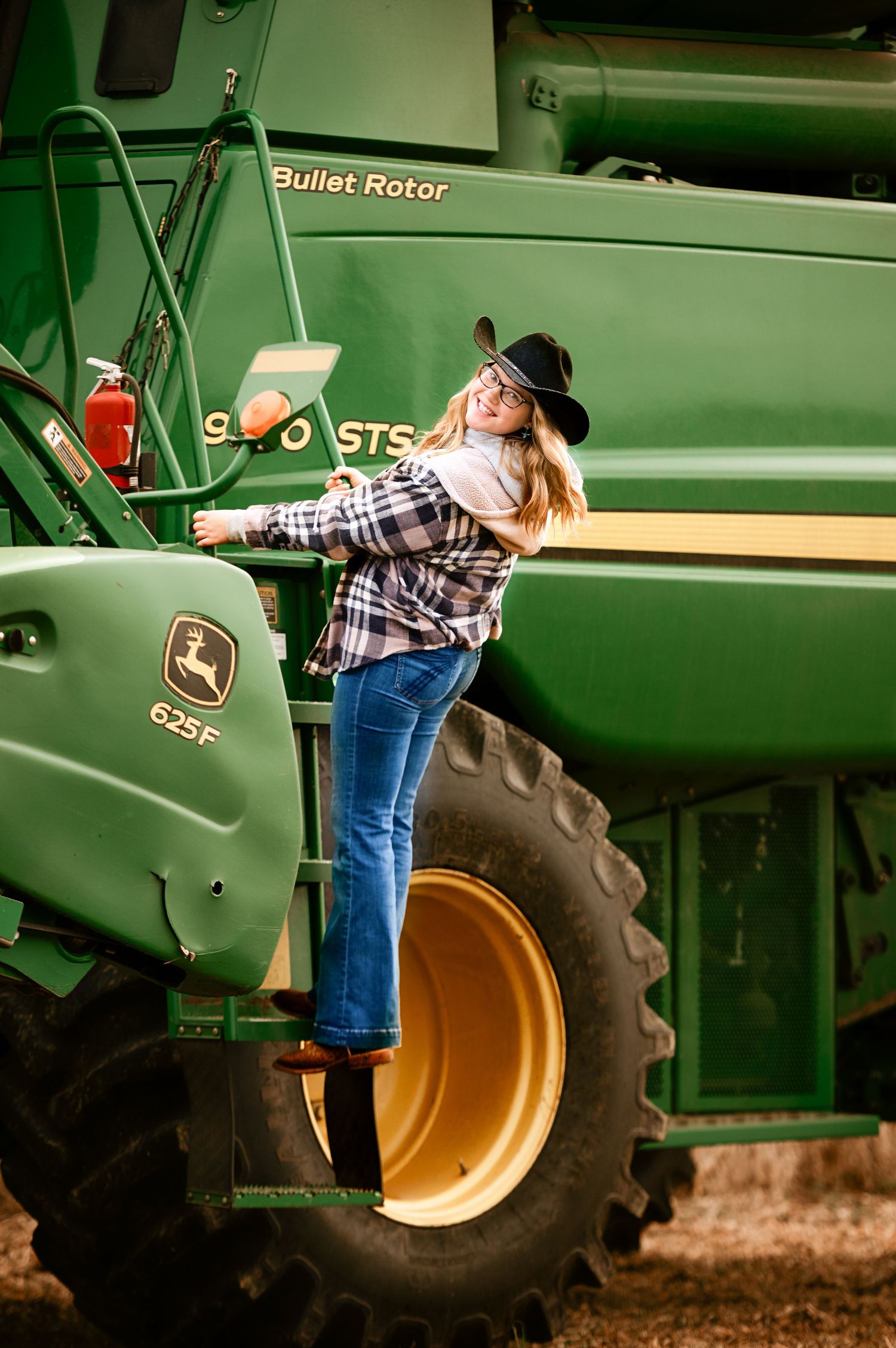 Creative portrait session with a large green John Deere combine harvester in an agricultural setting.