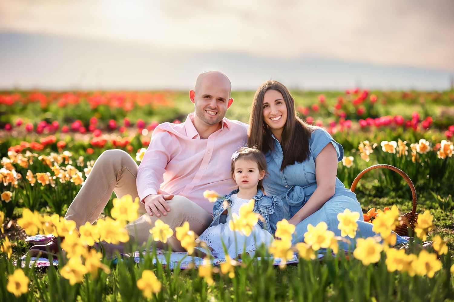 Family relaxes among blooming yellow and red tulips during a spring photo session.