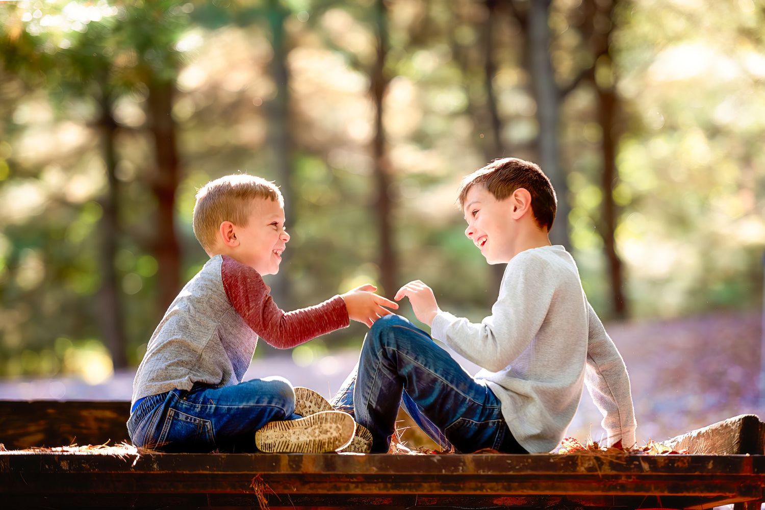 Two people interact playfully while sitting on wooden benches outdoors.