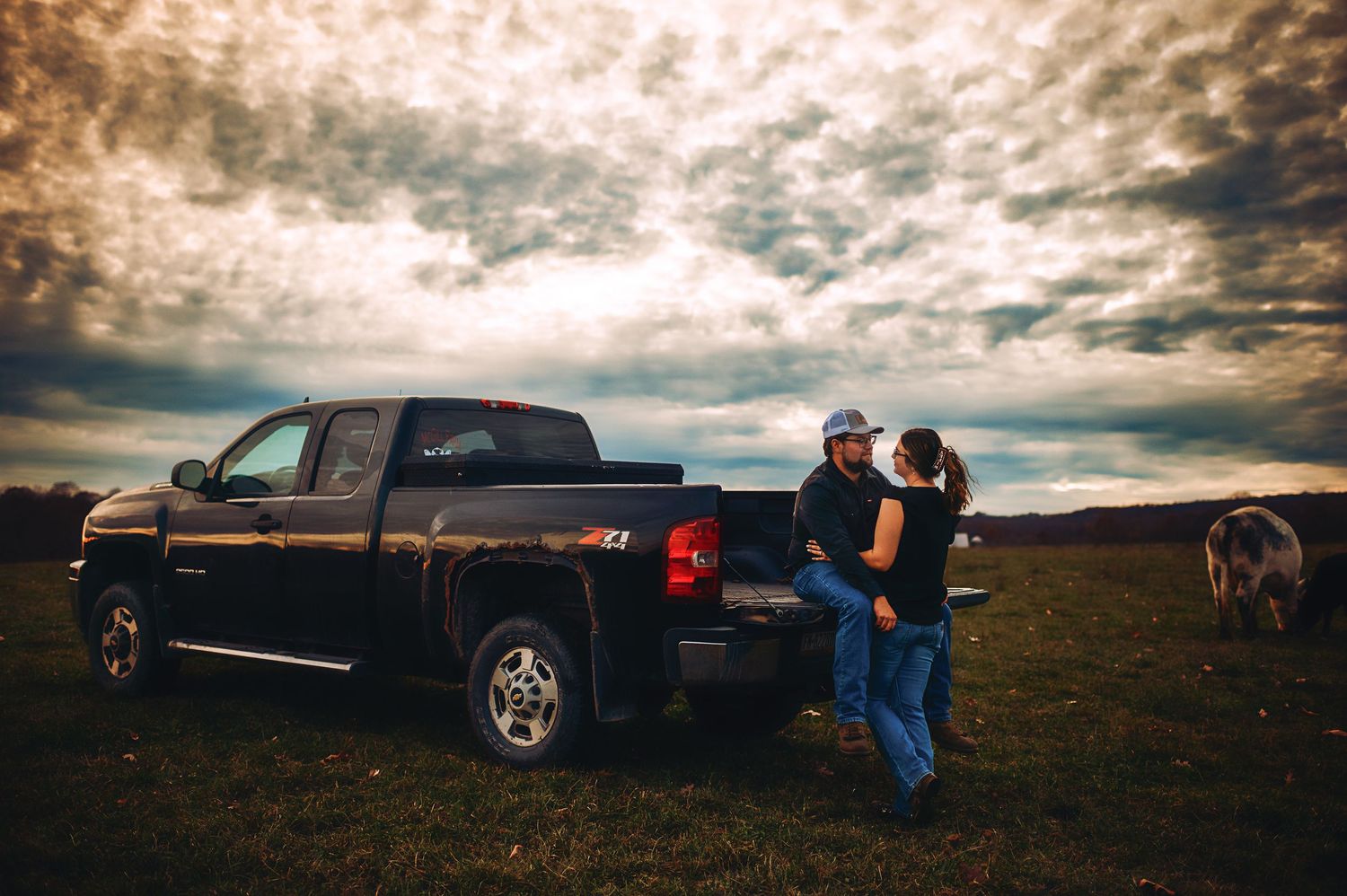 Silhouetted figures against dramatic sky with pickup truck in background.