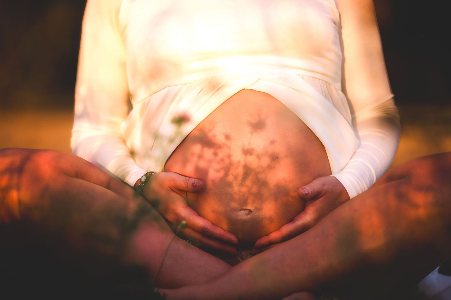 Intimate maternity photography with dramatic lighting and shadows.