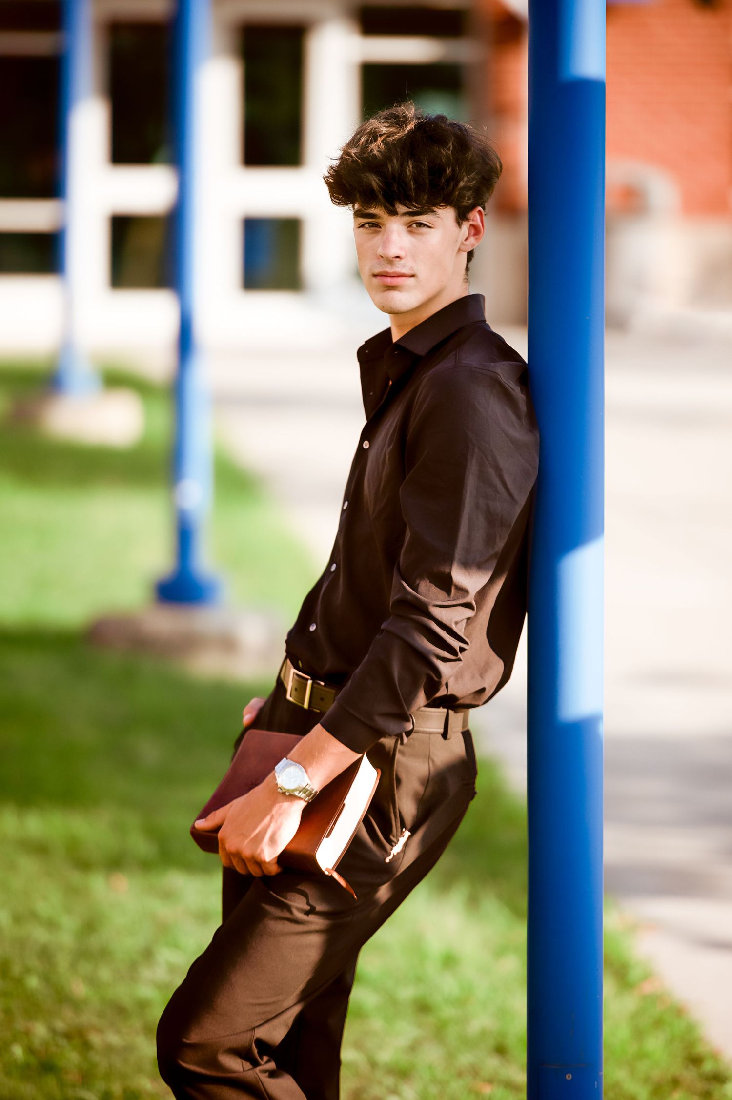 Creative portrait against blue pillars in casual black attire.