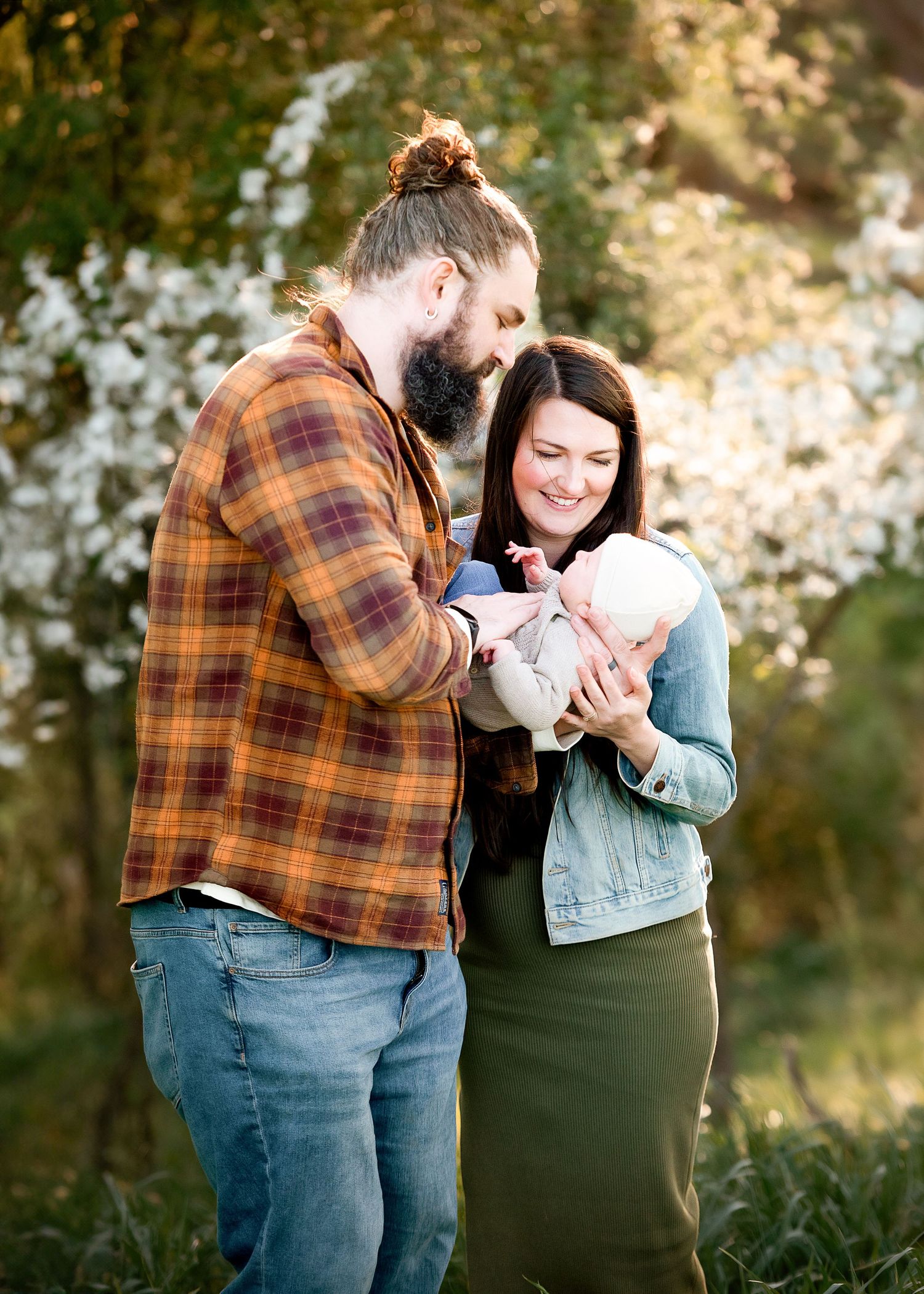 A couple shares a tender moment outdoors with autumn foliage in the background.