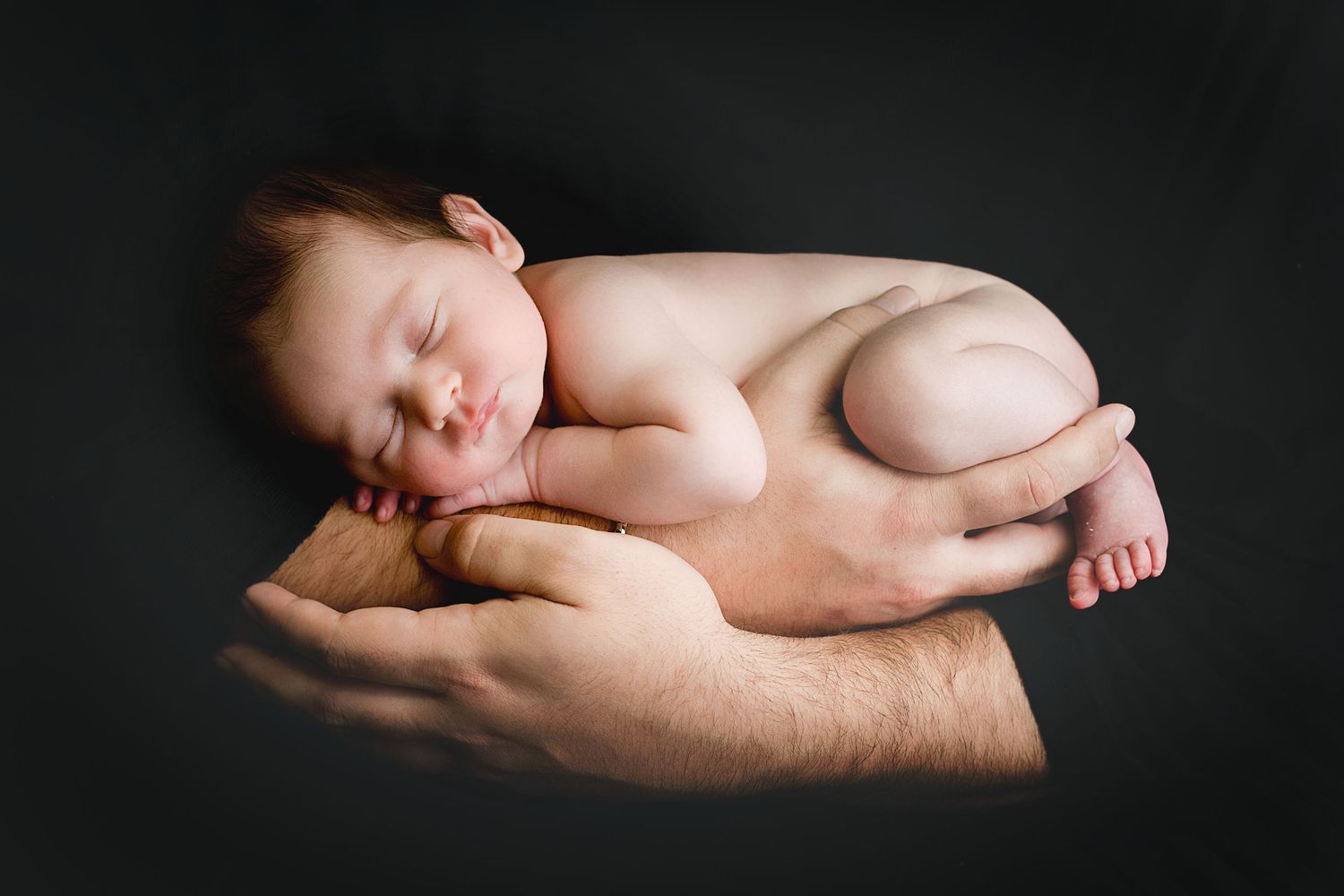 Series of artistic black and white newborn portraits on dark background.