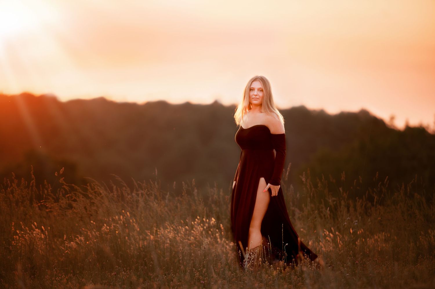 Silhouetted figure walking through tall grass at sunset in rural setting.
