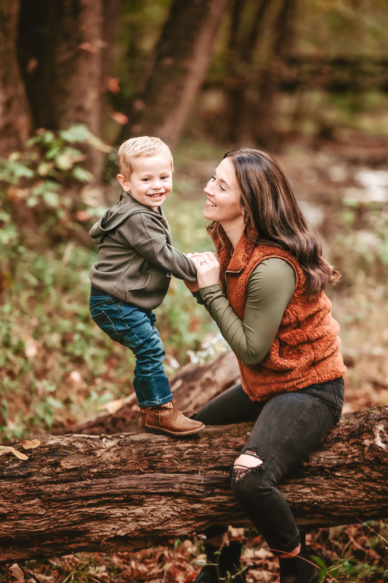 Playful autumn family moments on a fallen log in the woods.