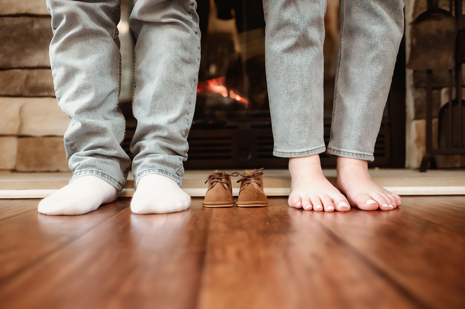 Close-up of feet and legs showing family members standing together on hardwood floor.