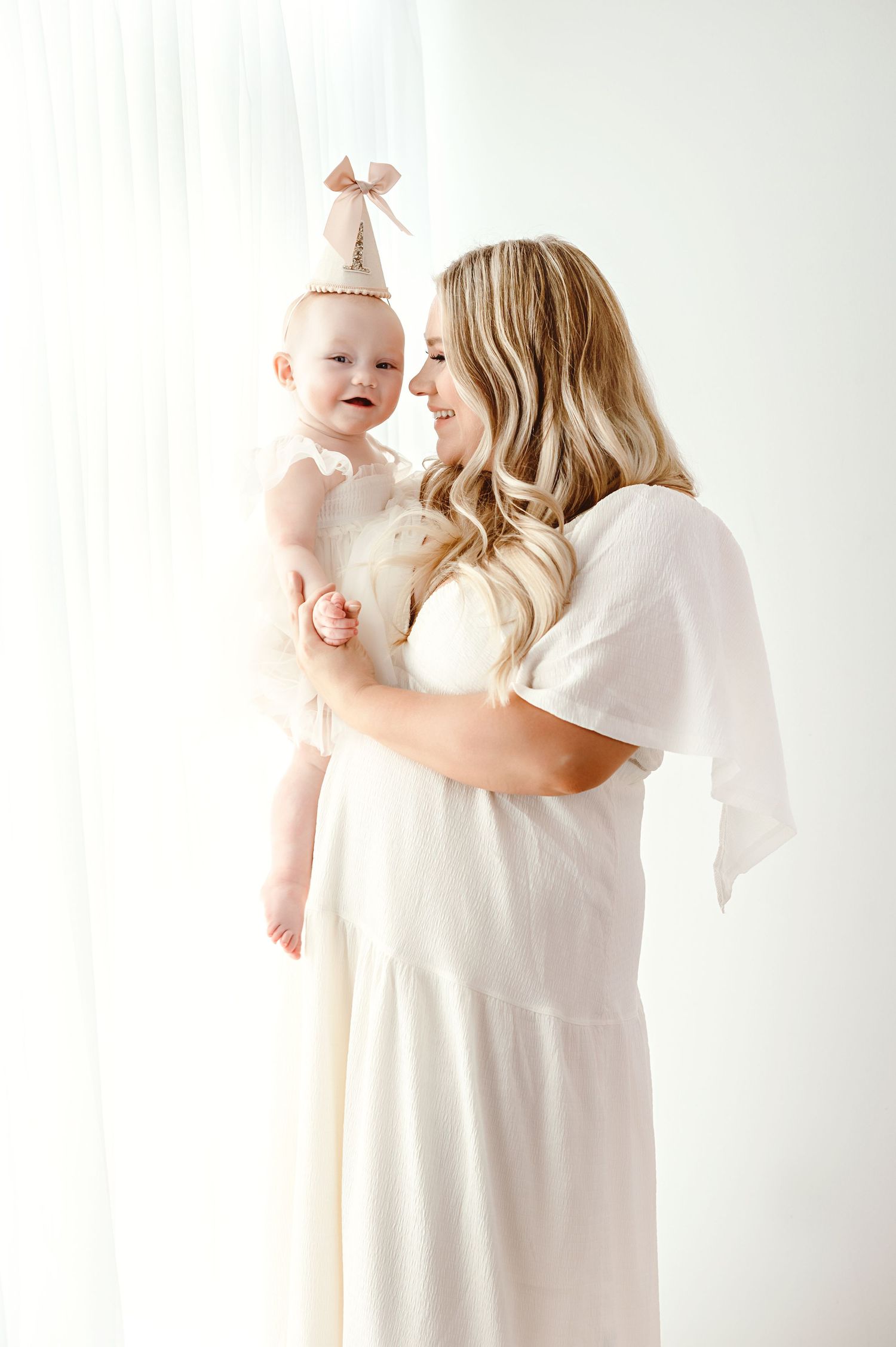 Sweet moments between parent and baby in white against minimal studio backdrop.