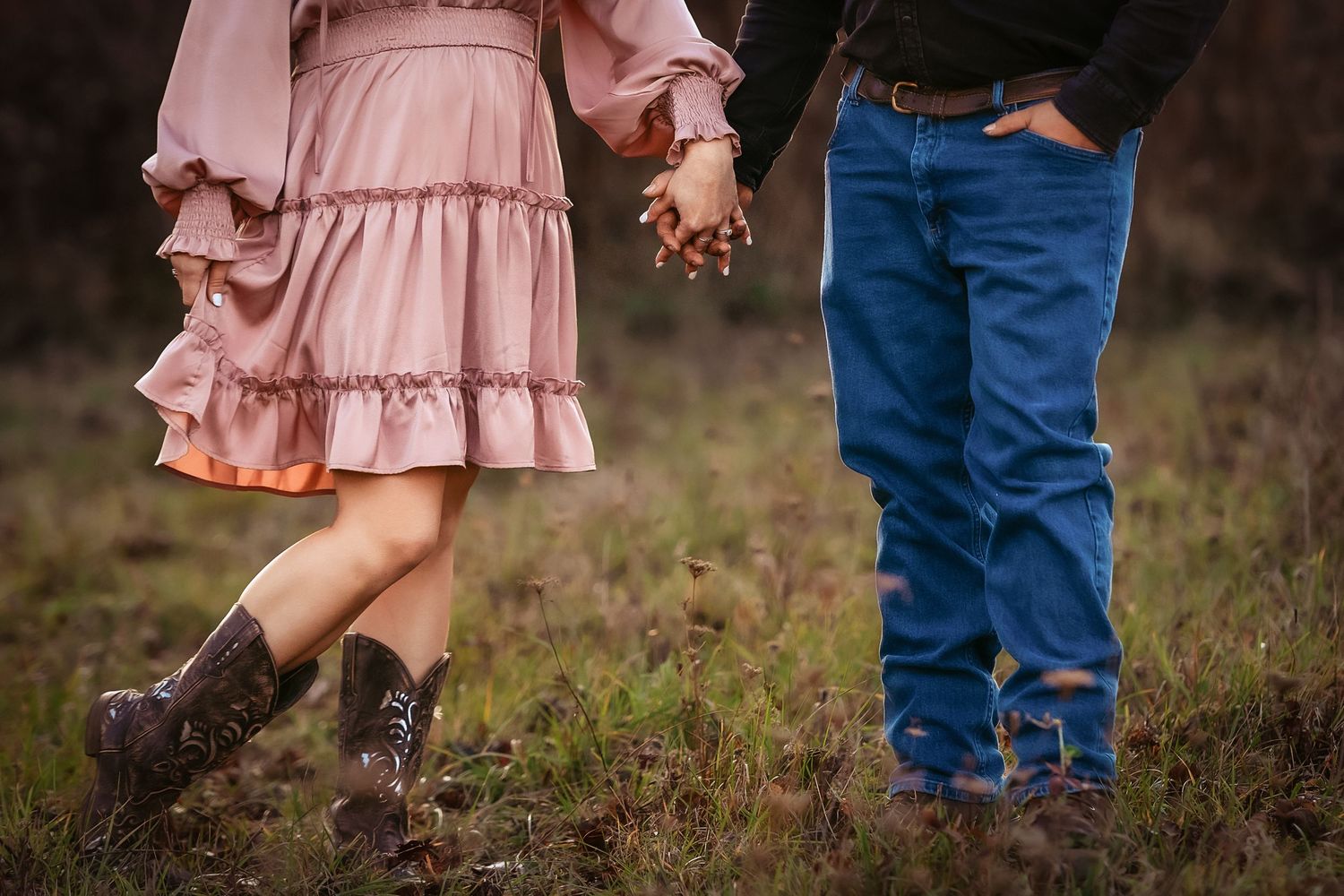 Pink dress and blue jeans contrast in a rustic outdoor setting.