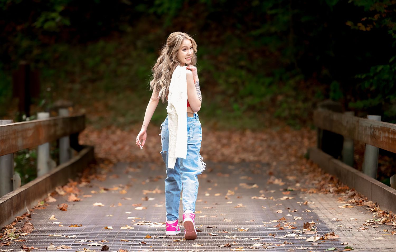 Person in denim walking along wooded path during autumn.