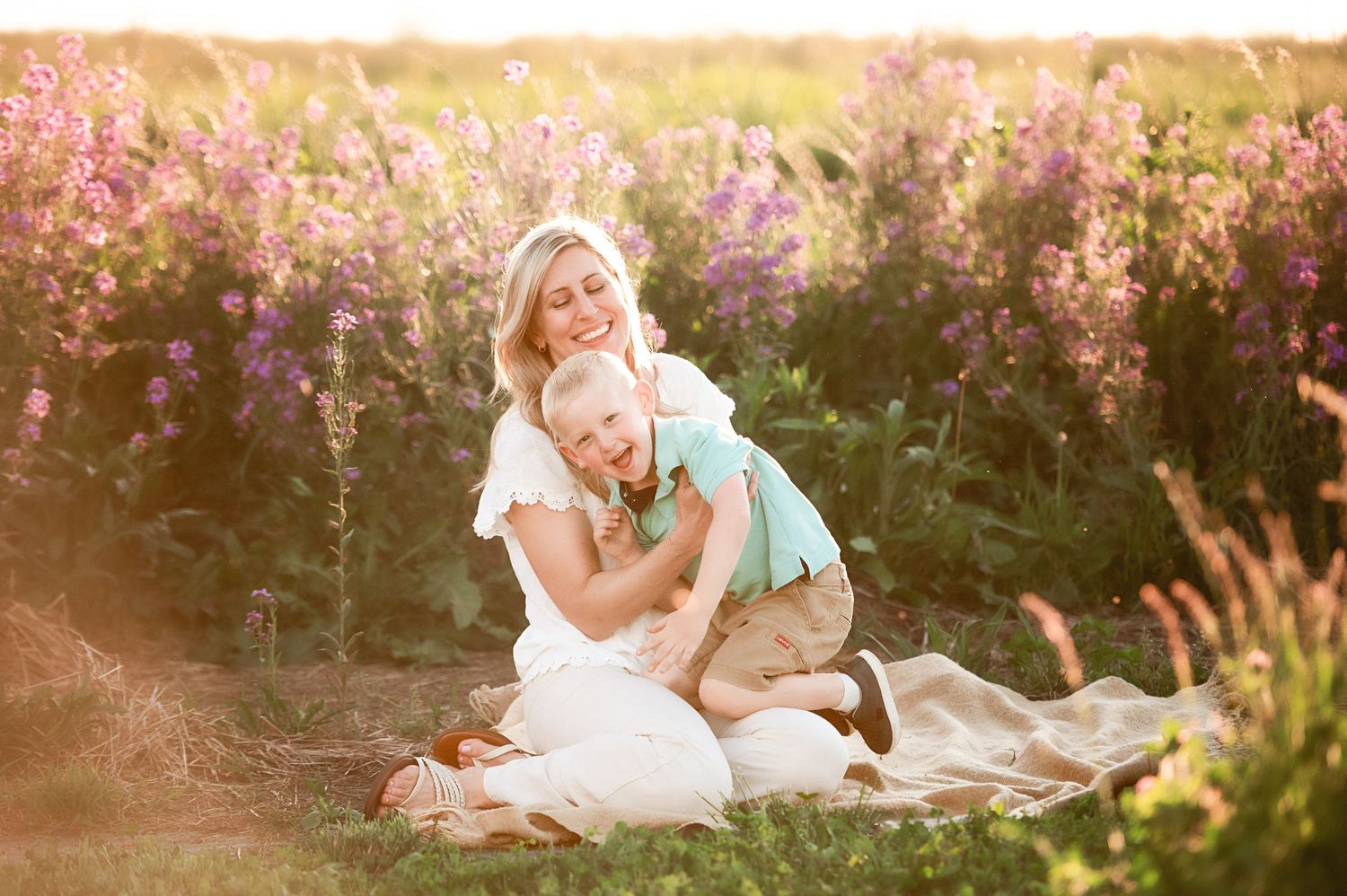 Family photo session in a field of pink wildflowers during sunset.
