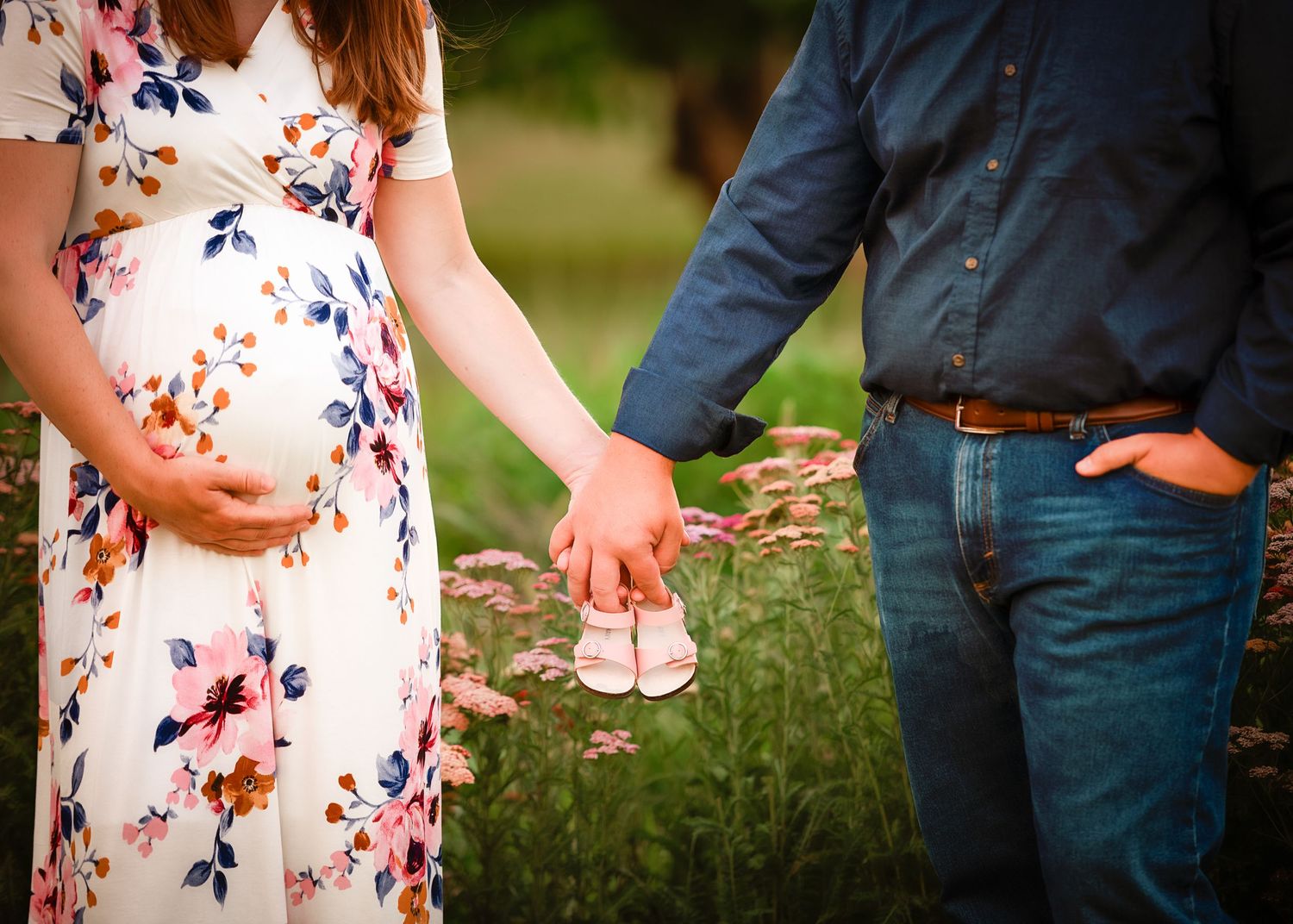 A couple in casual attire poses together in a garden setting with floral details.