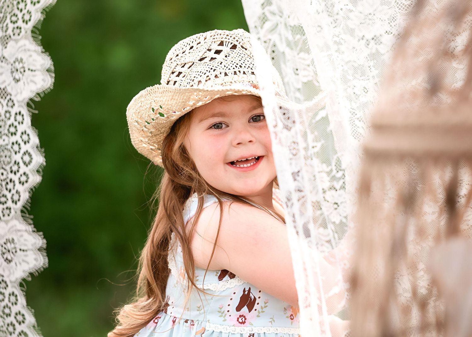 Child in a straw hat enjoying a sunny day outdoors.