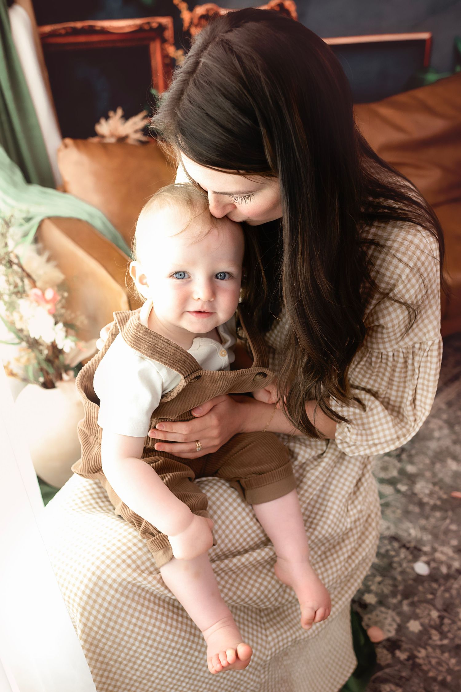 Mother and baby share intimate moments while sitting together in vintage-inspired setting.