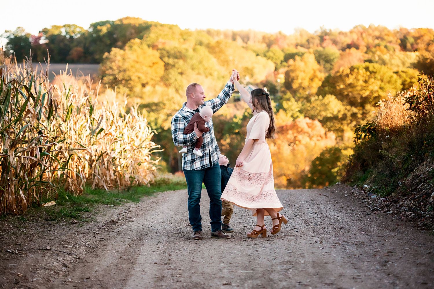 Family walks along scenic autumn trail with golden sunlight filtering through trees.