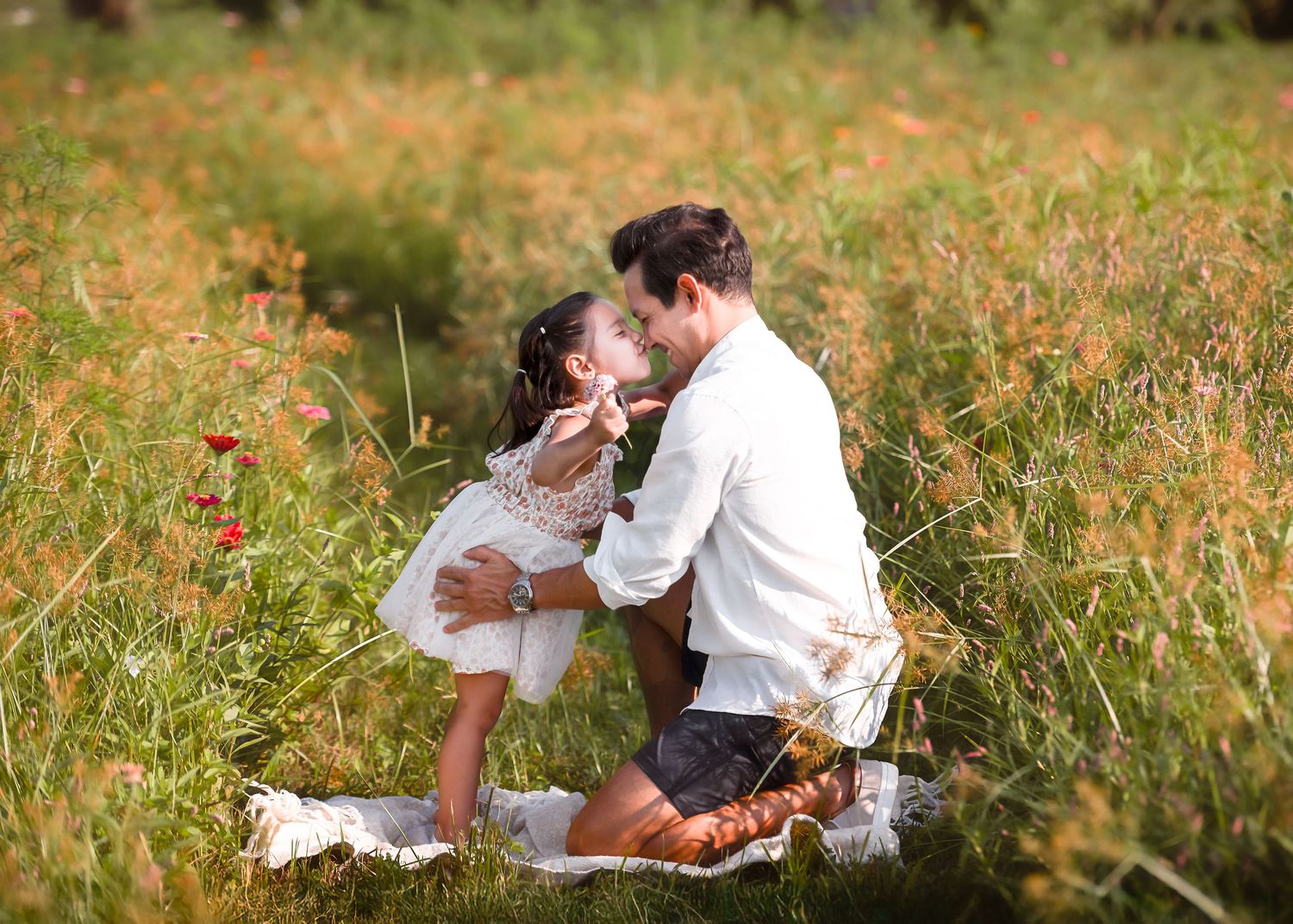 A couple relaxes together on a grassy hillside during a sunny afternoon.